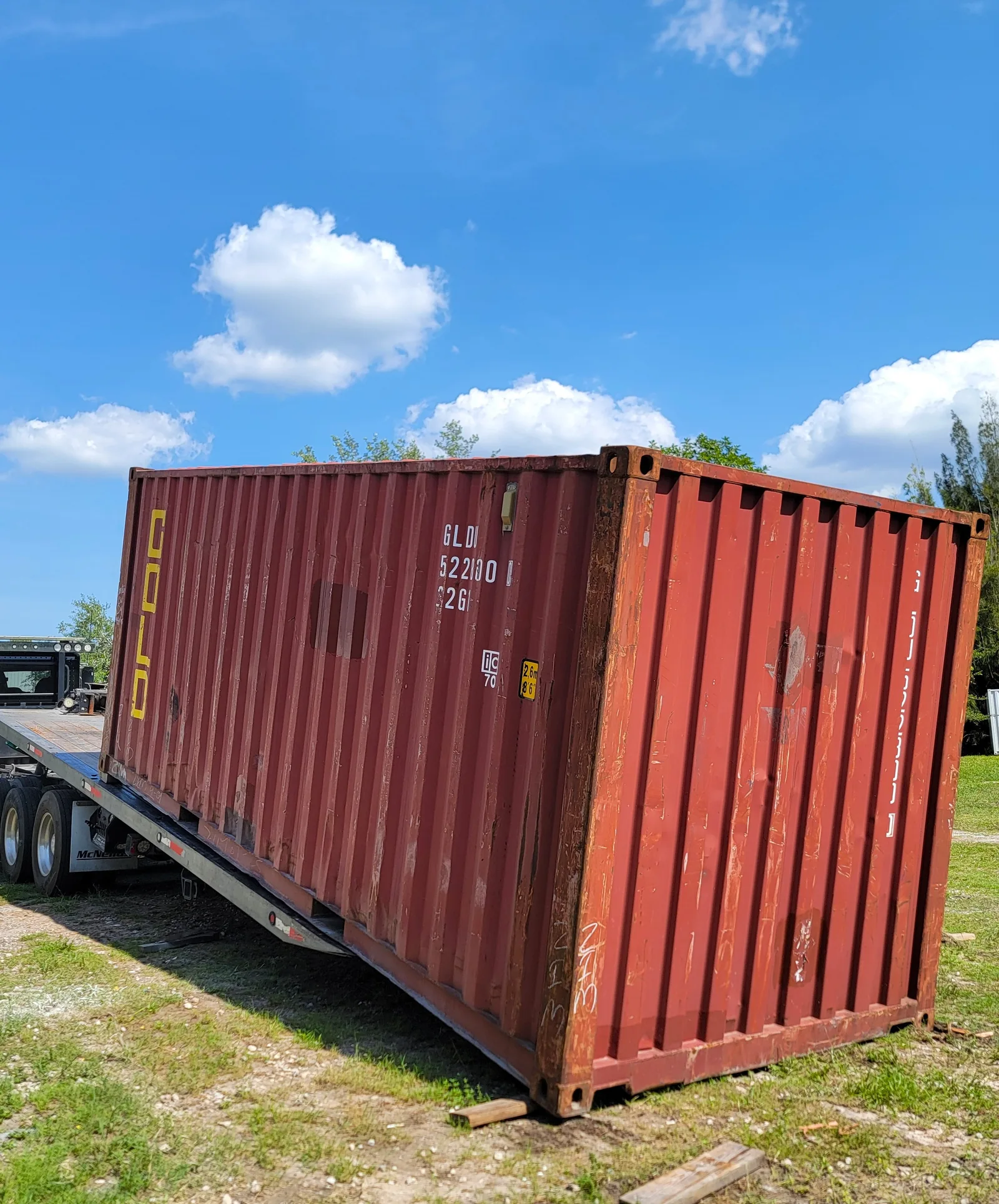 Used red shipping container on a delivery trailer.