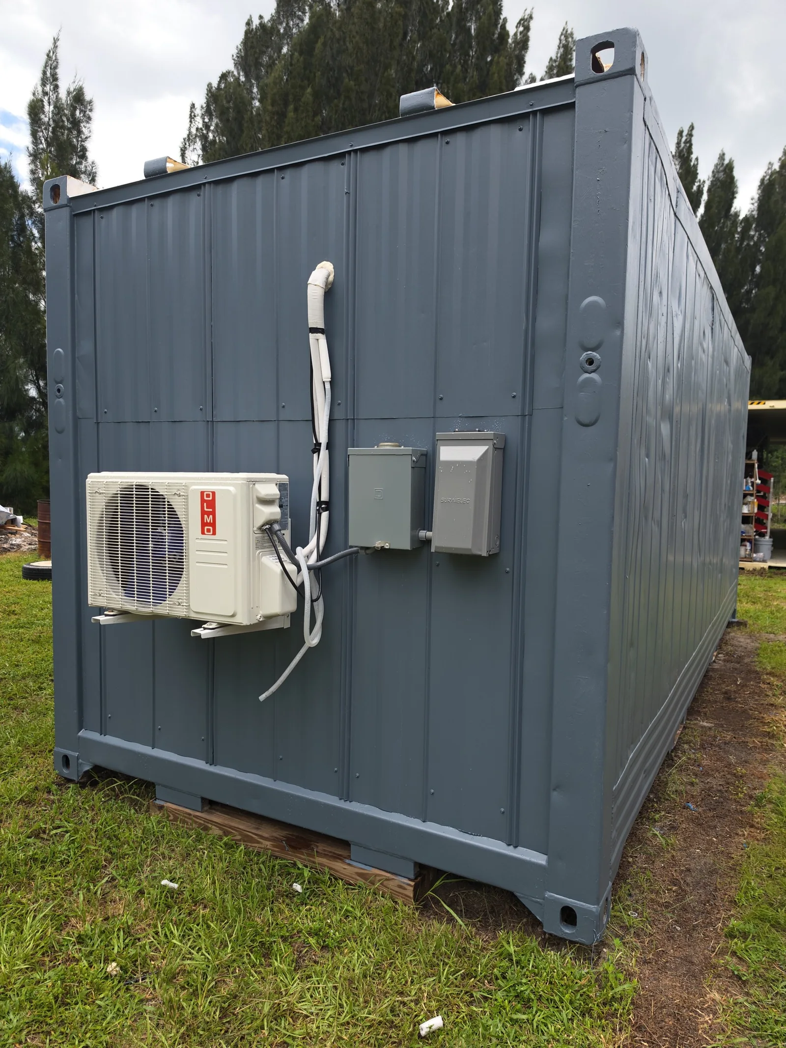 Exterior mini-split air conditioner installed on a gray modified shipping container.