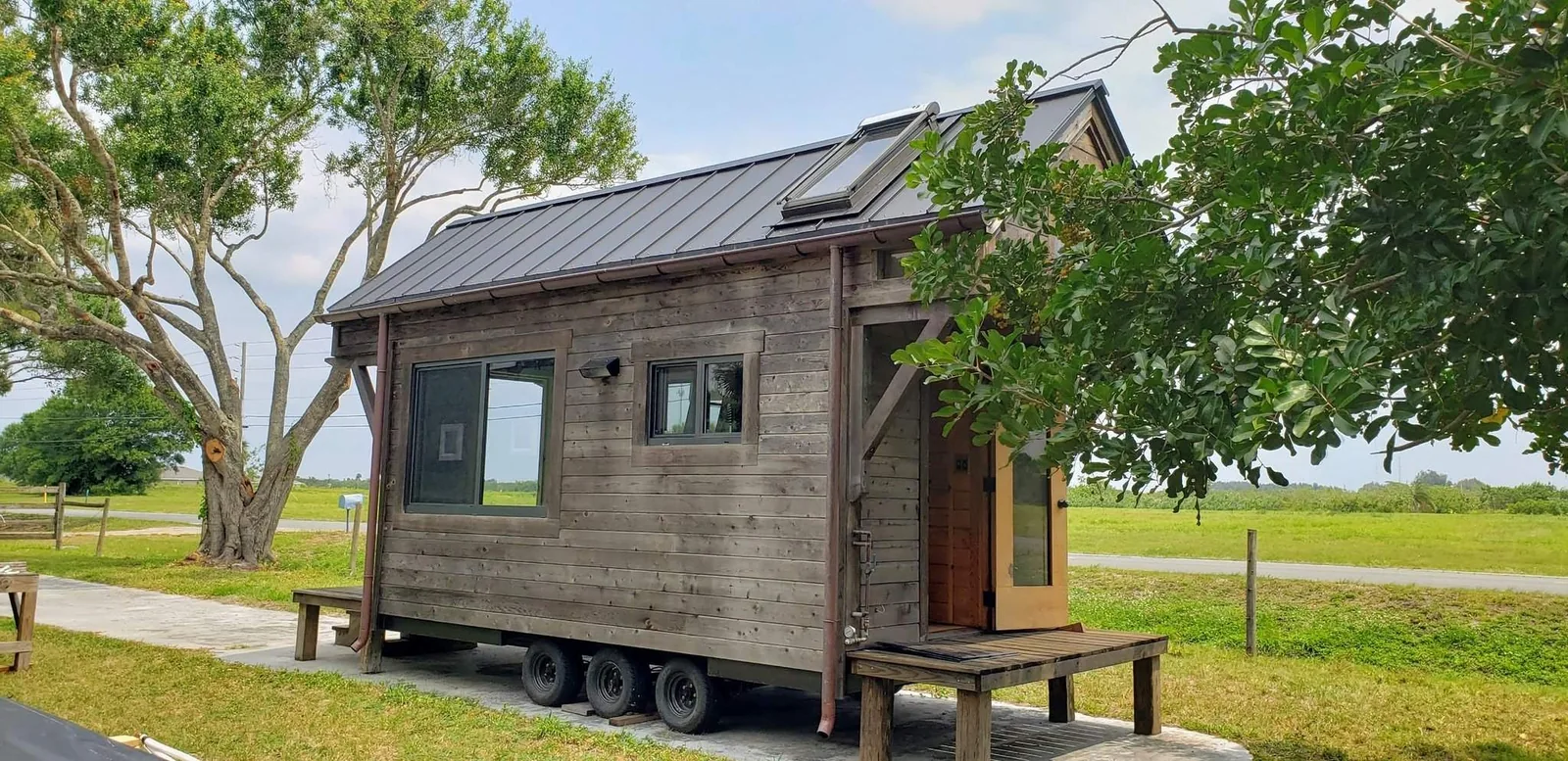 Wood-clad tiny house on wheels with a covered front porch.